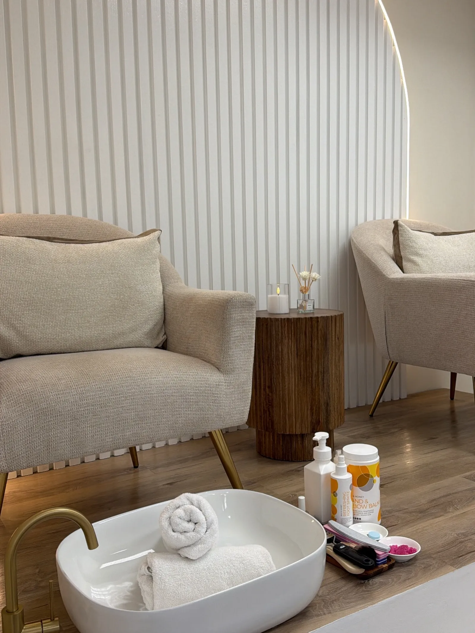 A treatment lounge at Elite Spa & Aesthetics, with a plush armchair, pedicure basin, and warm ambient lighting